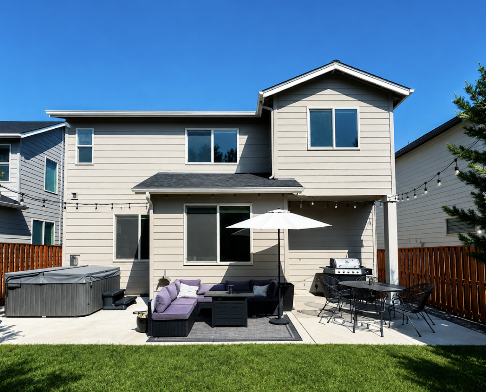 Two-story home with light neutral siding, white trim, and a backyard patio