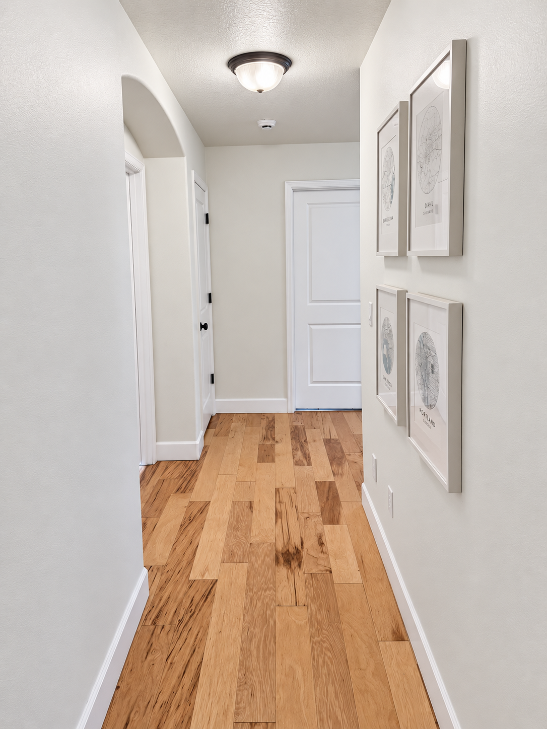 Bright hallway with neutral painted walls, white doors and trim, and warm wood flooring